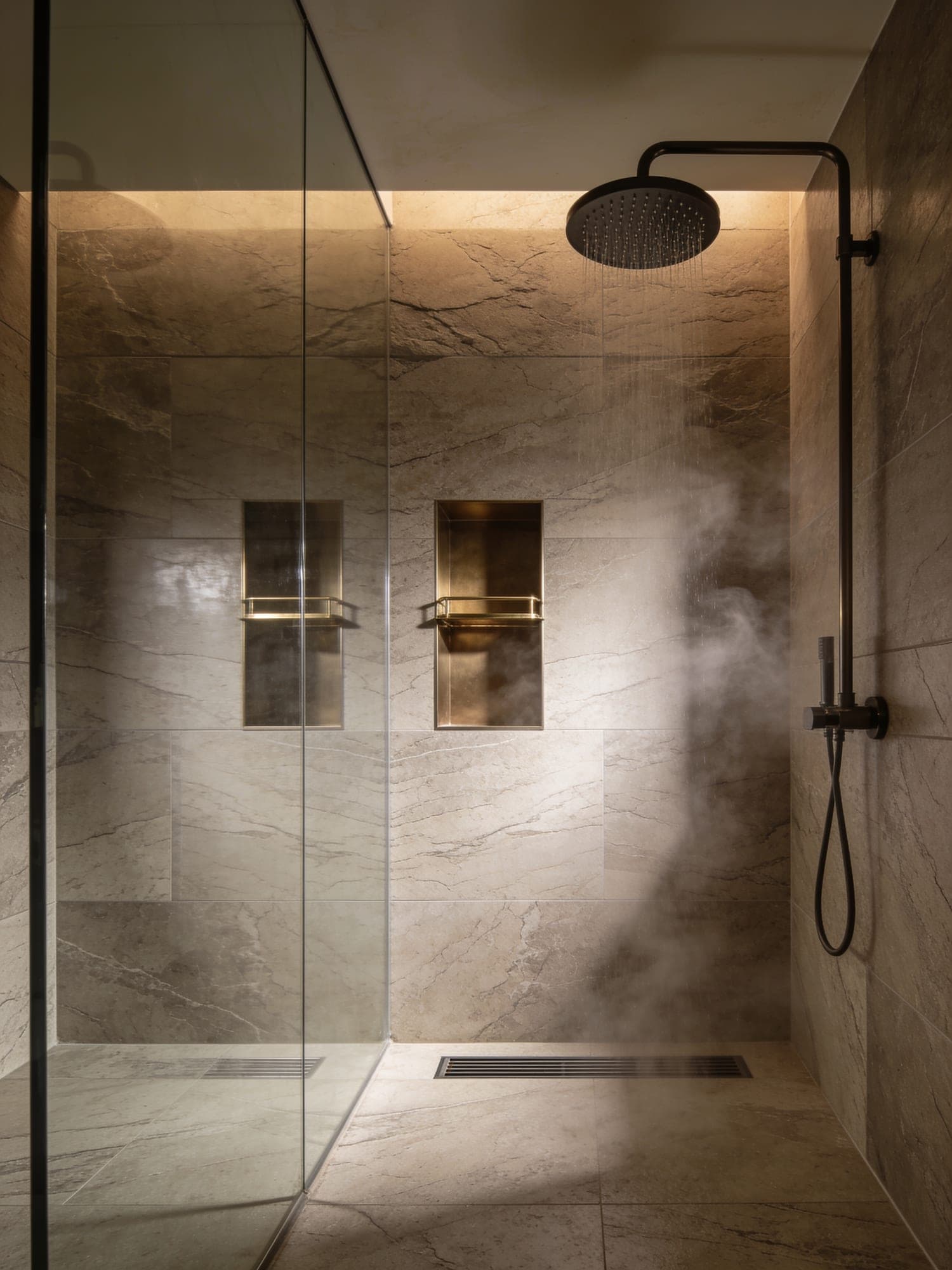 Walk-in shower lined with full height stone-look porcelain slabs and a linear drain