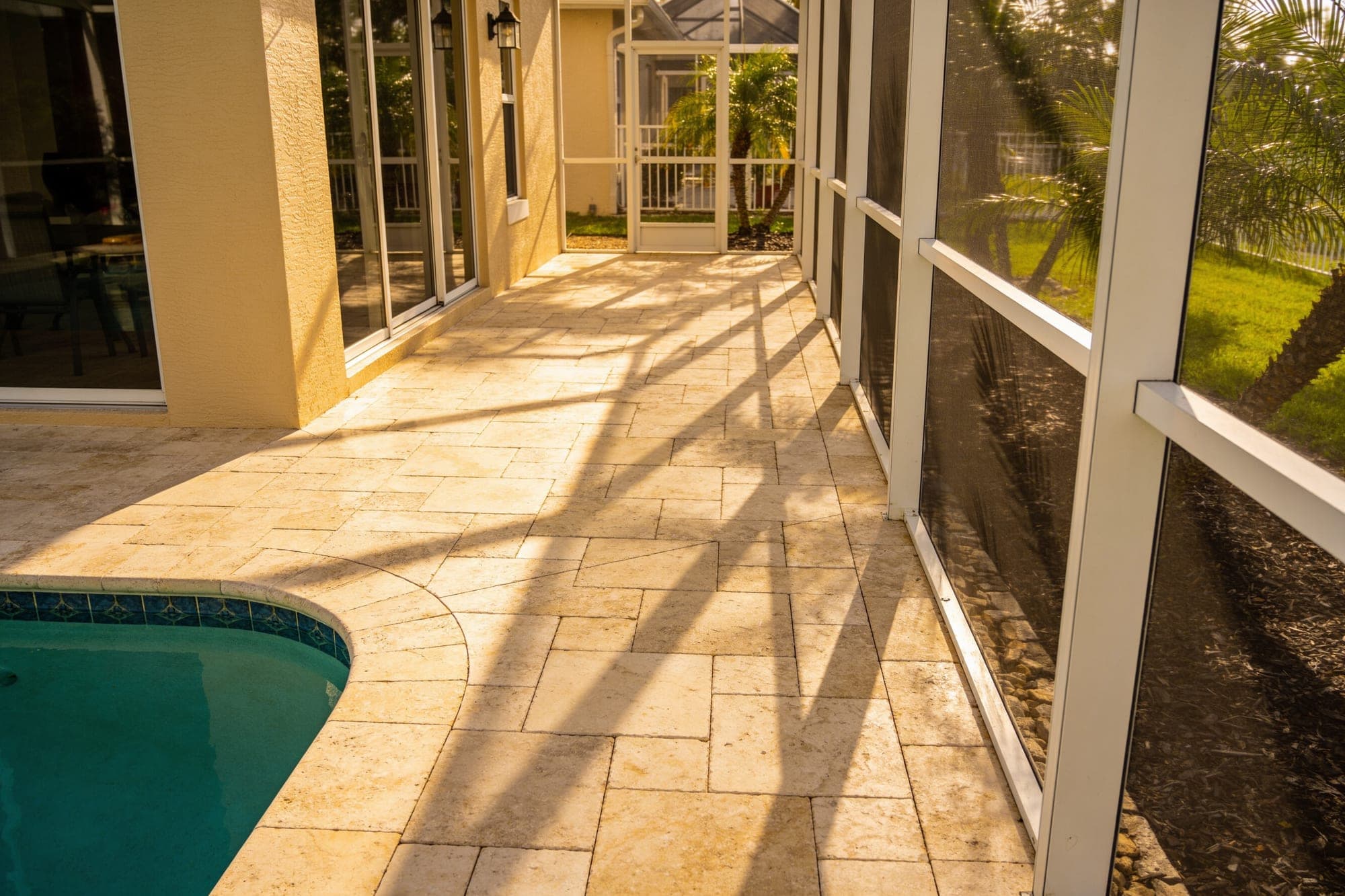 Backyard pool deck paved in French pattern travertine